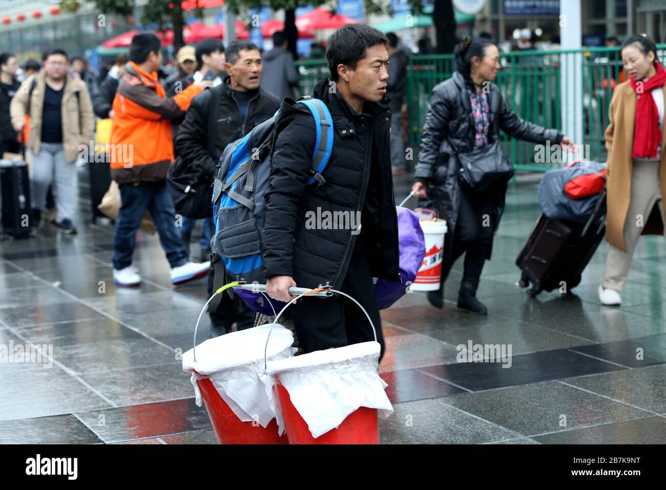 Passagiere tragen Plastikeimer, der ihr Gepäck enthält, und bereiten sich darauf vor, an Bord des Zuges zu gehen, der zu Hause am Shanghaier Bahnhof, Shanghai, China, ist. Stockfoto
