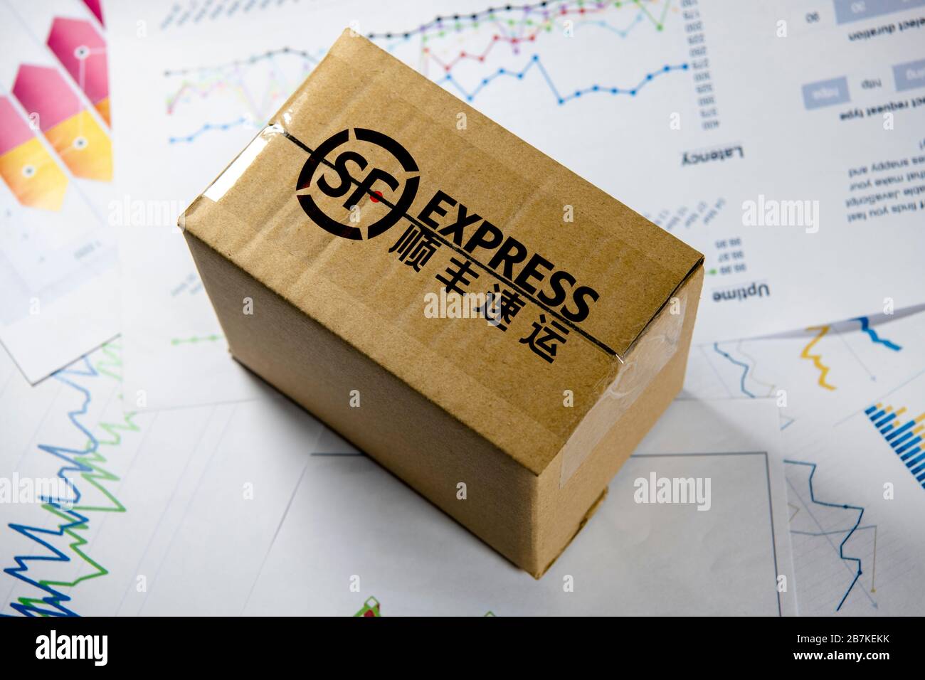 Kreatives Foto: Ein SF Express-Paket wird auf einen Stapel Papier gelegt. Stockfoto