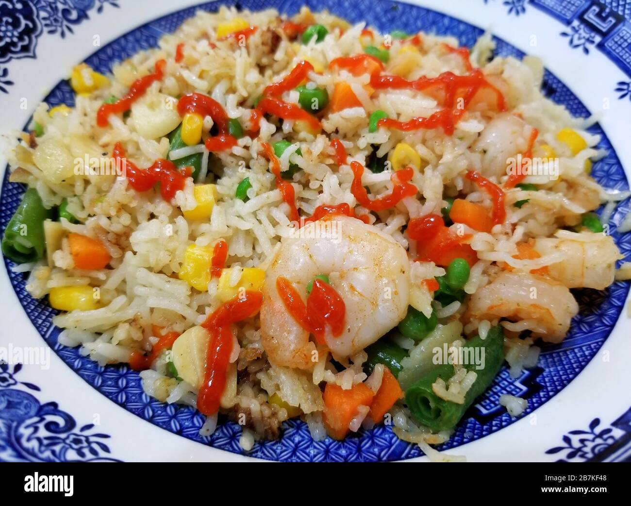Gebratener Reis mit Garnelen, gemischtem Gemüse und Sriracha-Sauce Stockfoto