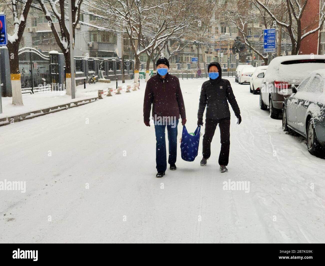 Menschen wandern im Schnee mit einem Beutel mit Gegenständen in Peking, China, 6. Februar 2020. Stockfoto