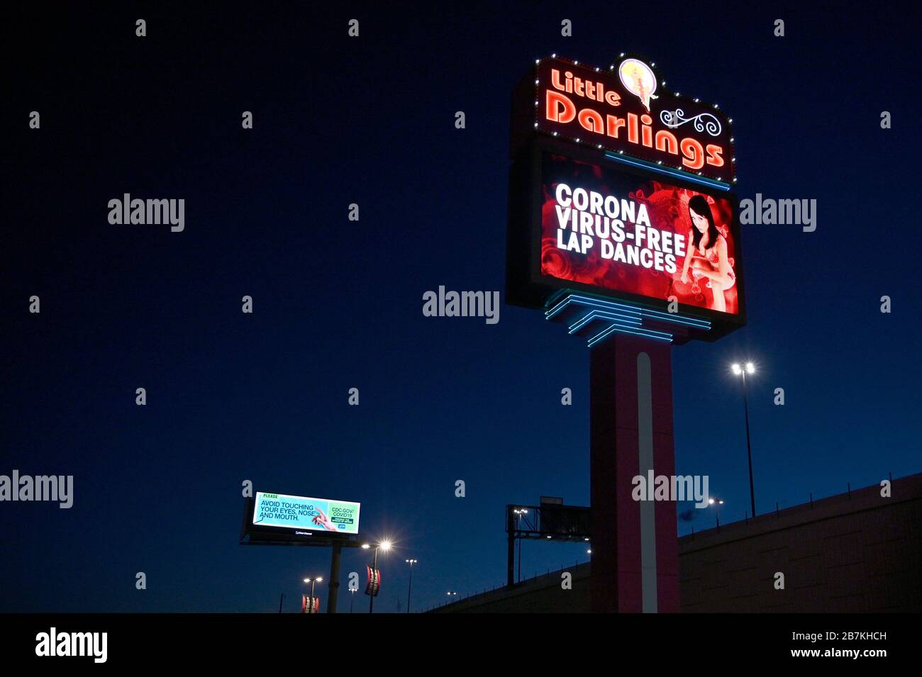 Las Vegas, Nevada, USA. März 2020. Ein Schild im Las Vegas Strip Club wirbt für "Coronavirus-freie Runde tanzt", da ein Center for Disease Control and Prevention Public Service Ankündigungs-Plakat im Hintergrund angezeigt wird, das "vermeiden Sie das Berühren Ihrer Augen, Nase und Mund" am 16. März 2020 in Las Vegas, Nevada wirbt. Die Weltgesundheitsorganisation erklärte das Coronavirus (COVID-19) am 11. März zu einer globalen Pandemie. Credit: David Becker/ZUMA Wire/Alamy Live News Stockfoto