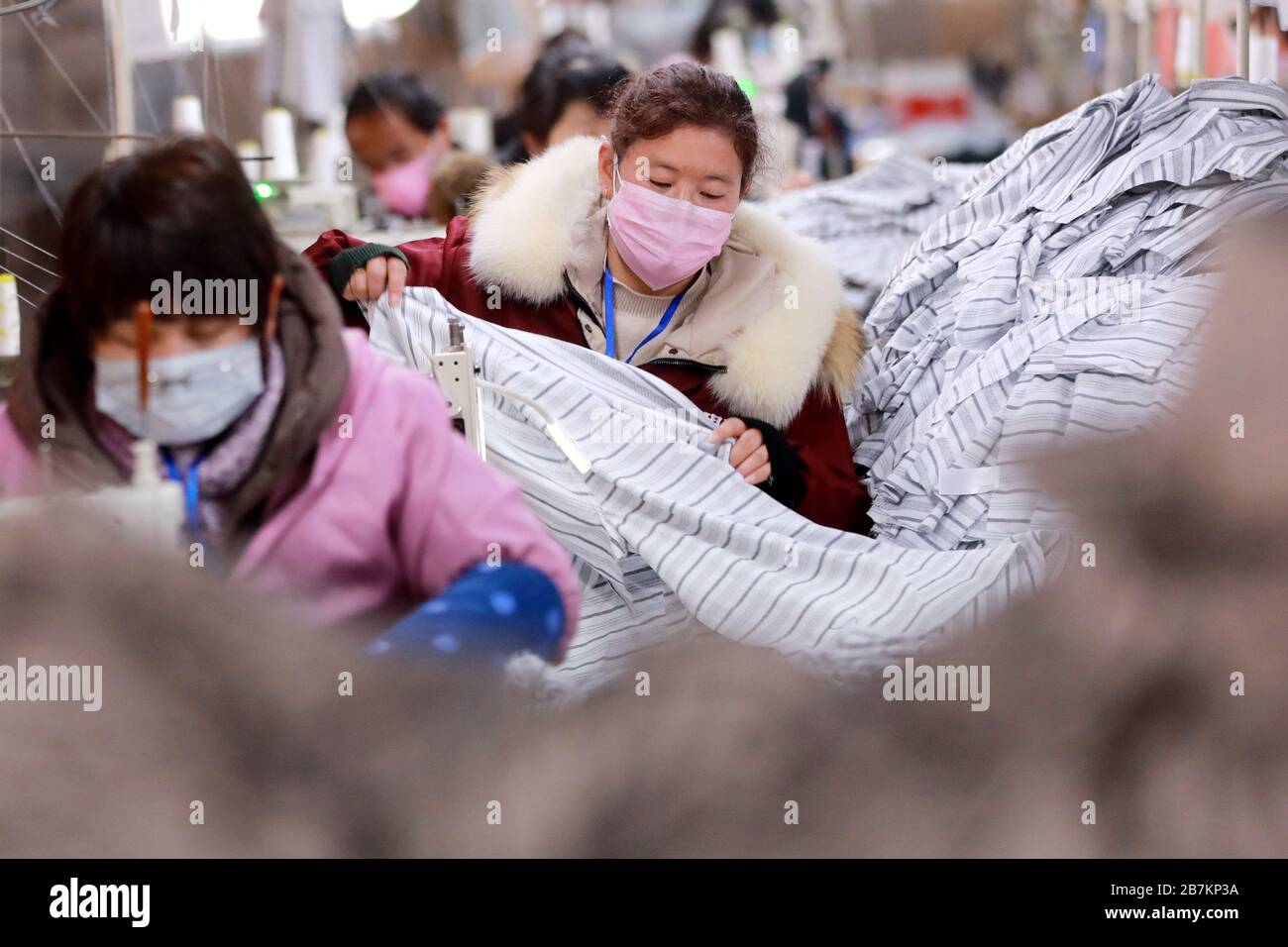 Die Mitarbeiter einer Kleiderfabrik sind nach langen Ferien auf dem Frühlingsfest mit Maske beschäftigt, Bezirk Suixi, Stadt Huaibei, Ostchina Anhui Stockfoto