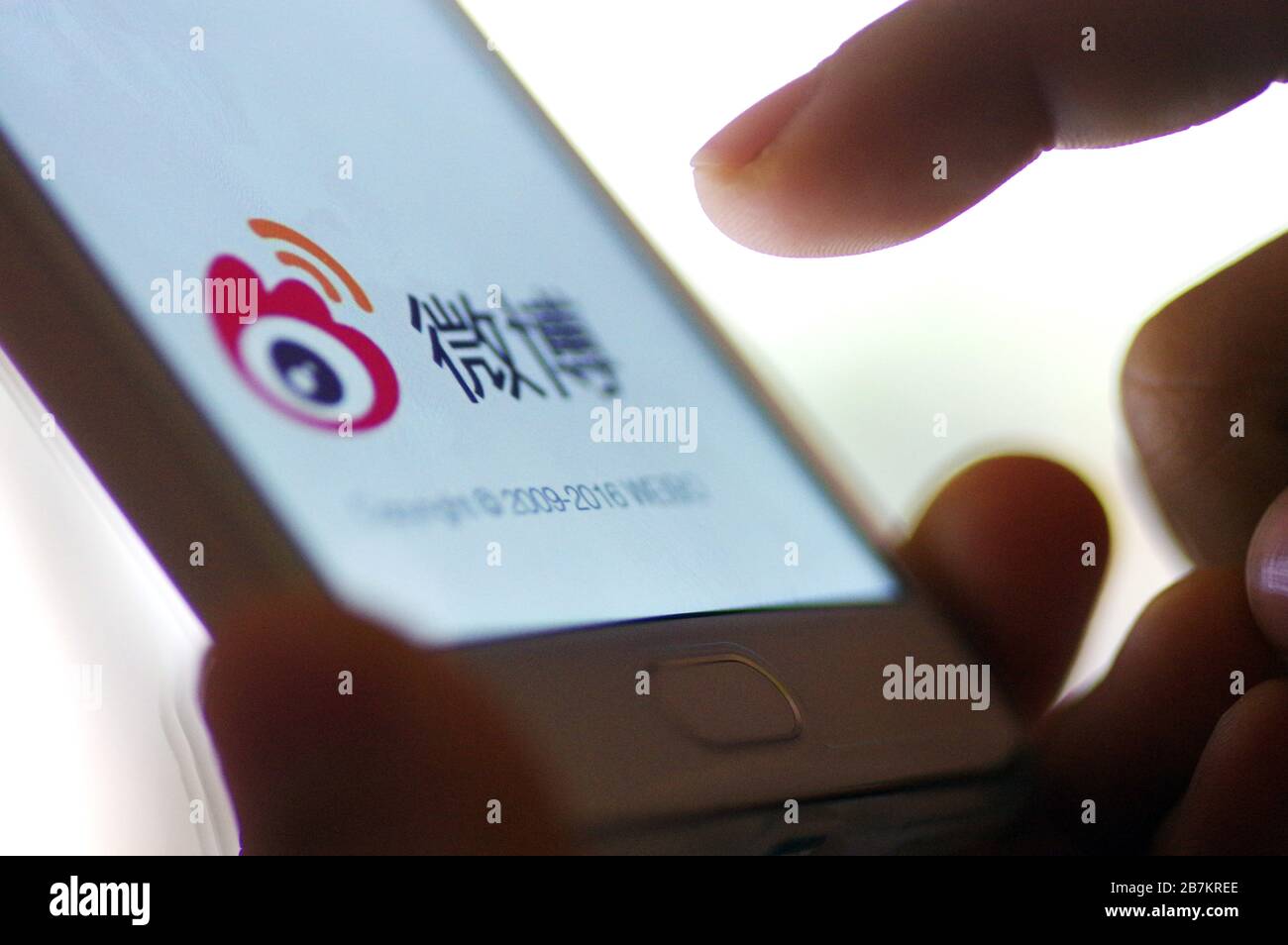 Kreatives Foto: Das Logo von Sina Weibo, einer chinesischen Microblogging-Website (weibo) ähnlich wie Twitter, wird auf einem Smartphone gezeigt, wie der Besitzer es verwendet. Stockfoto