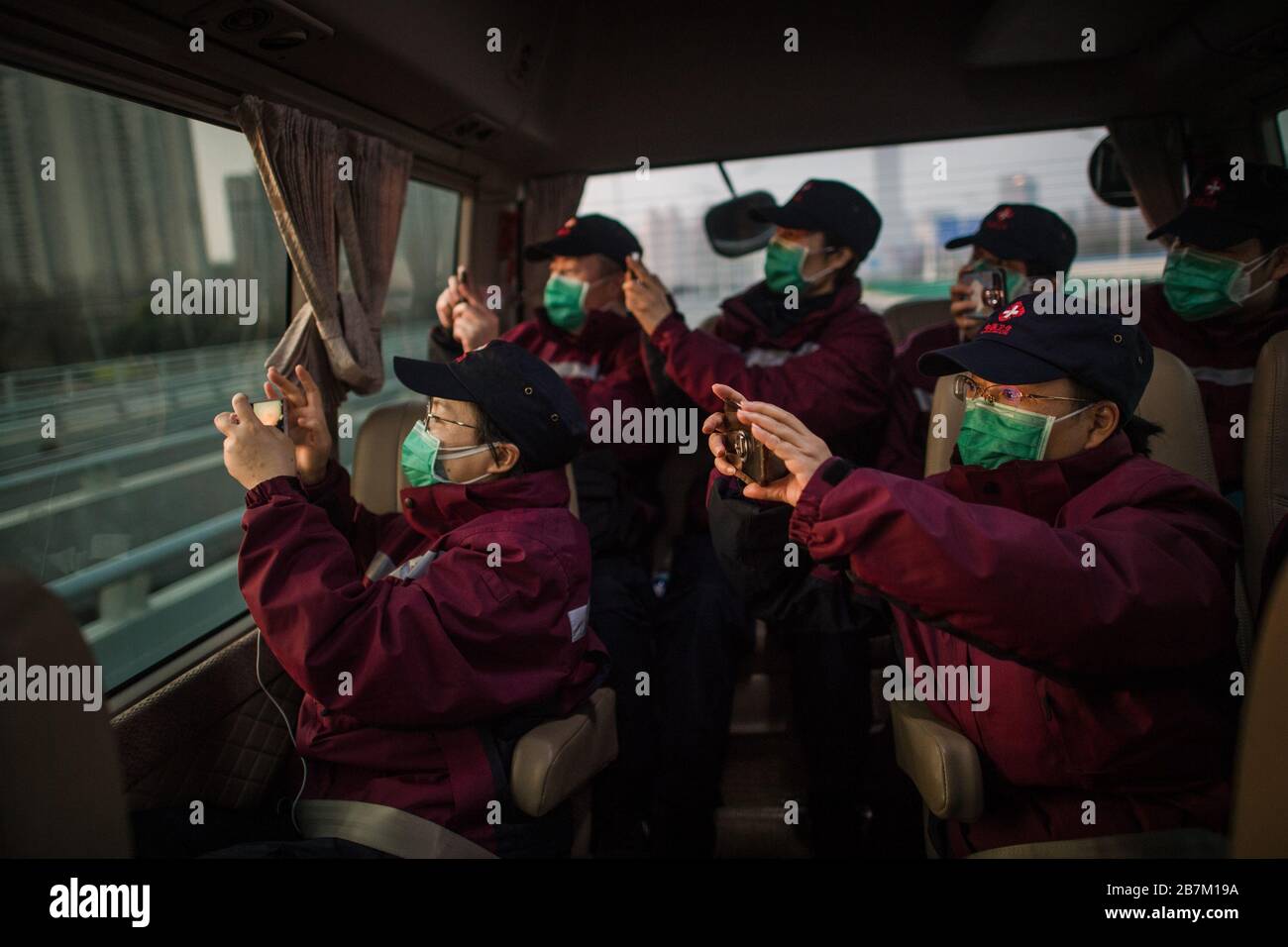 (200317) -- WUHAN, 17. März 2020 (Xinhua) -- Medics aus der nordwestchinesischen Provinz Shaanxi machen Fotos von der Stadtansicht mit ihren Mobiltelefonen in einem Bus in Wuhan, der zentralchinesischen Provinz Hubei, am 17. März 2020. Gegen 7 Uhr am Dienstag verließen 43 Sanitäter aus der nordwestchinesischen Provinz Shaanxi Wuhan in neun Bussen. Die erste Reihe von Sanitätern soll Hubei, einst die schwer angeschlagene Provinz des neuartigen Coronavirus, am Dienstag verlassen haben, da die epidemische Situation stark gelockert wurde. Die 3.675 medizinischen Mitarbeiter von 41 medizinischen Teams aus ganz China haben 14 Versuchoren unterstützt Stockfoto