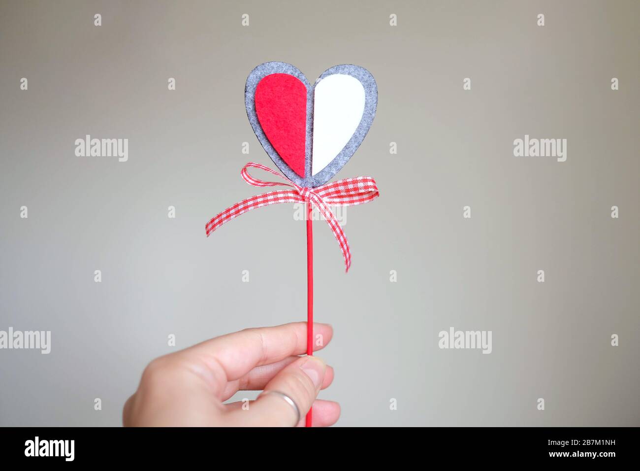 Halten Sie ein dekoratives Herz an einem Stock in der Hand. Das Herz befindet sich in der Mitte. Valentinstag. Stockfoto