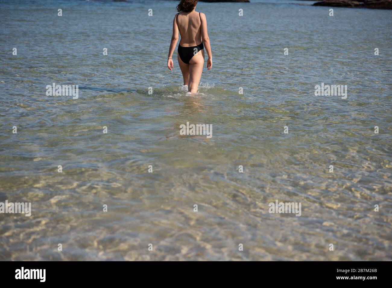 Junge Frau, die ins Wasser kommt, um zu schwimmen Stockfoto