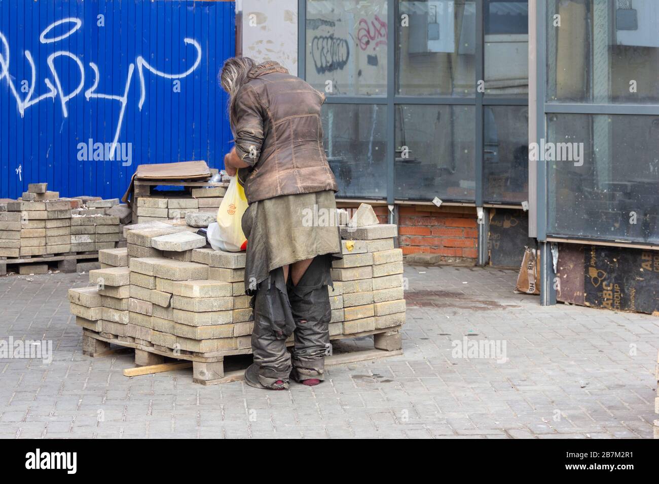 Krasnodar, Russland - 11. Februar 2020: Ein Mann ein Bettler ein Tramp in zerrissenen Hosen mit einem Beutel Essen steht auf der Straße Stockfoto