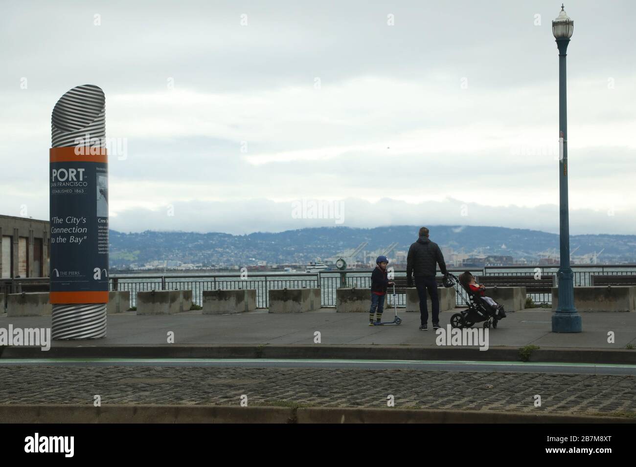 San Francisco, USA. März 2020. Ein Mann spaziert mit seinen Kindern am Meer in San Francisco, den Vereinigten Staaten vom 16. März 2020. Sechs Bezirke in der Region Bay Area im Norden Kaliforniens, darunter San Francisco, kündigten am Montag eine öffentliche Gesundheitsordnung an, in der die Bewohner aufgefordert werden, zu Hause zu bleiben, mit Ausnahme wesentlicher Aktivitäten. Kredit: Liu Yilin/Xinhua/Alamy Live News Stockfoto