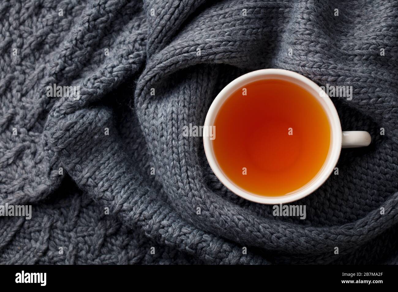 Tasse Tee. Grau gestrickter Schal Hintergrund. Kopierbereich. Draufsicht. Stockfoto