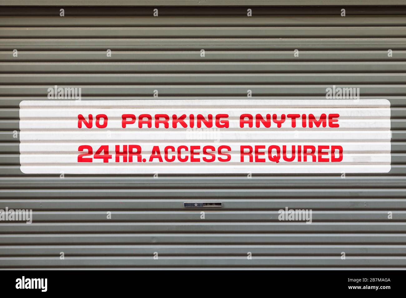 Schild, kein Parkplatz, 24-Stunden-Zugang an der Rollentür erforderlich Stockfoto