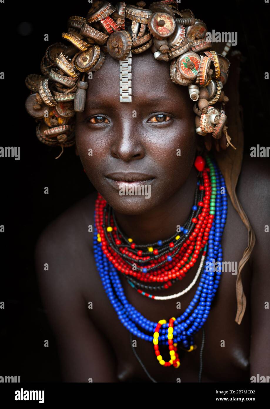 Porträt einer jungen Dassanech nette Frau tragen Flasche Kappen Kopfbedeckungen und Perlen Halsketten-Omo-Tal-Äthiopien Stockfoto
