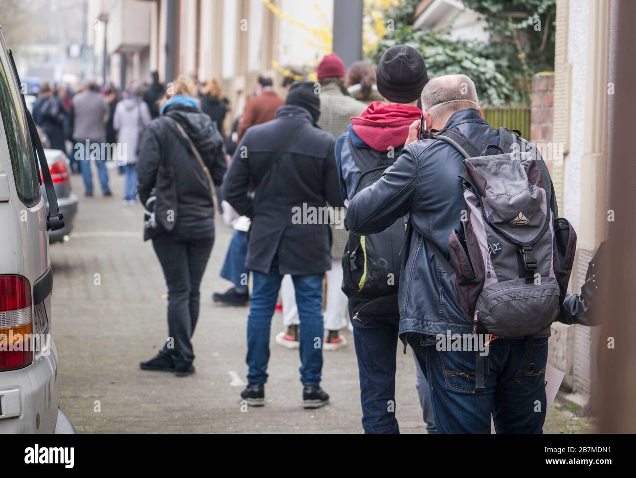 17. März 2020, Hessen, Frankfurt am Main: Die Menschen warten in einer langen Warteschlange auf dem Bürgersteig im Corona-Testzentrum des medizinischen Bereitschaftsdienstes Hessen. Die Testzentren für Corona-Virusschmierungen in Hessen sind überarbeitet. Auch wenn der Verband der gesetzlichen Krankenversicherungsärzte (KV) die Kapazitäten weiter ausbaut, so sind die Labore der Engpass. Jeden Morgen bilden sich lange Warteschlangen. Foto: Frank Rumpenhorst / dpa Stockfoto 17. März 2020, Hessen, Frankfurt am Main: Die Menschen warten in einer langen Warteschlange auf dem Bürgersteig im Corona-Testzentrum des medizinischen Bereitschaftsdienstes Hessen. Die Testzentren für Corona-Virusschmierungen in Hessen sind überarbeitet. Auch wenn der Verband der gesetzlichen Krankenversicherungsärzte (KV) die Kapazitäten weiter ausbaut, so sind die Labore der Engpass. Jeden Morgen bilden sich lange Warteschlangen. Foto: Frank Rumpenhorst / dpa Stockfoto