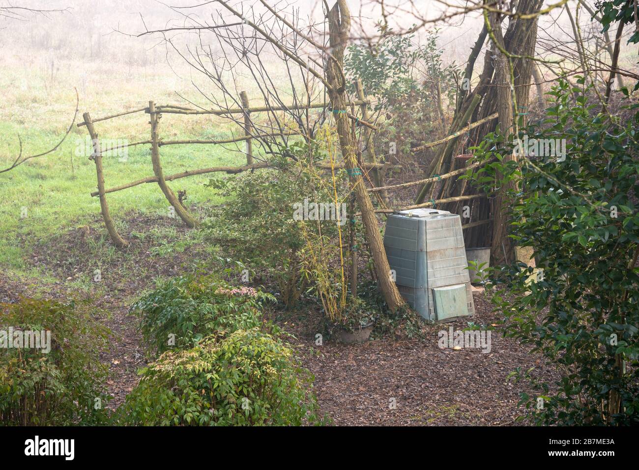 Kunststoff-Kompostbehälter in einem Hinterhof eines Bauernhauses an einem kalten und nebligen Wintermorgen Stockfoto