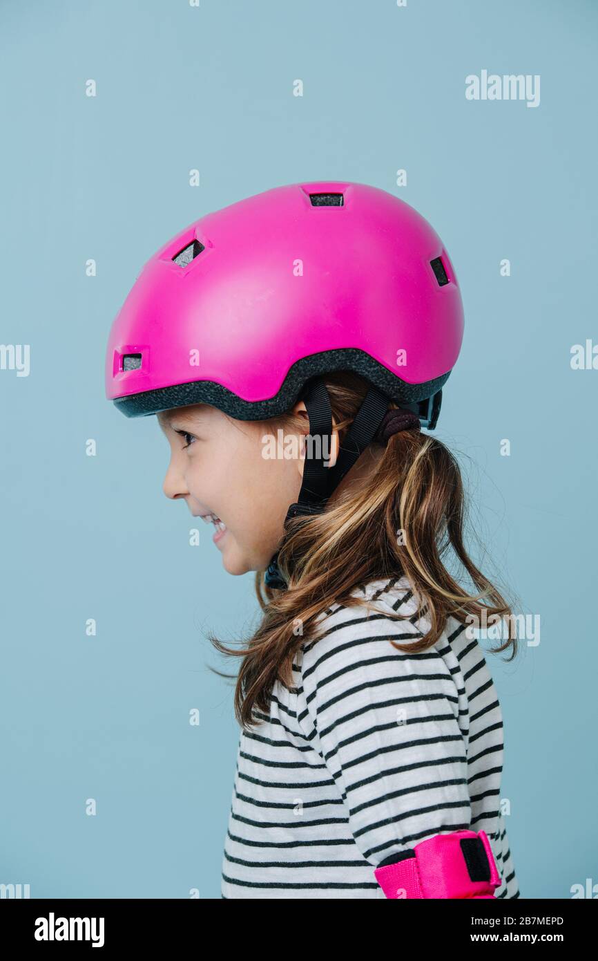 Porträt des Vorschoolers in pinkfarbenem Helm auf dem Boden Stockfoto