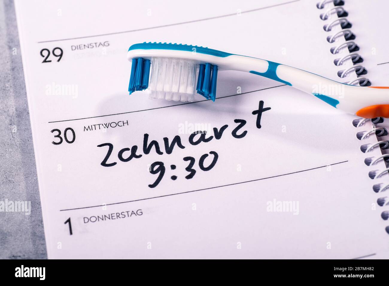 Kalender, auf dem eine Zahnbürste platziert wird und in den ein Termin für einen Zahnarztbesuch eingetragen ist Stockfoto