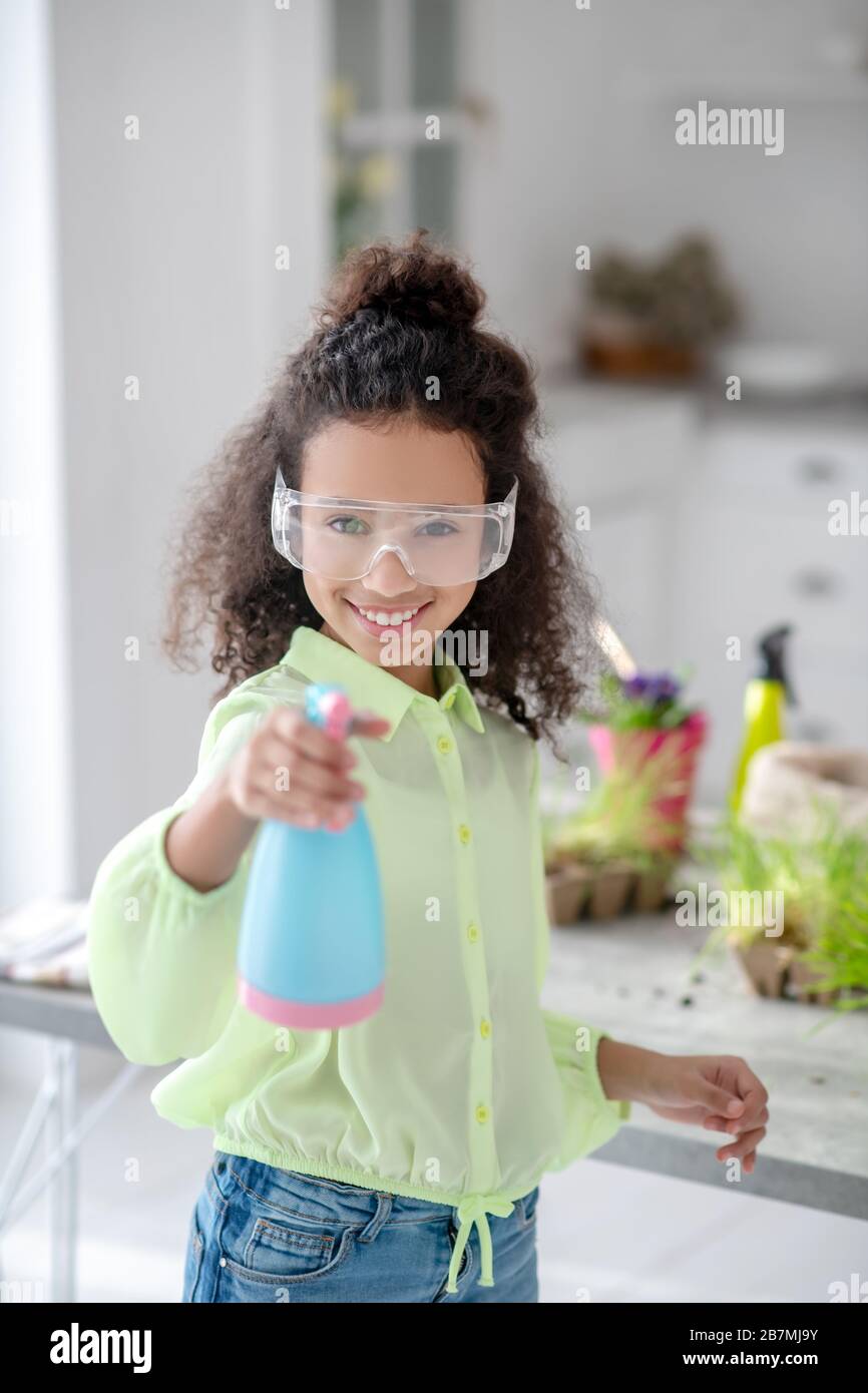 Lustige Mädchen in einer Brille mit einem Wasserspray in der Hand. Stockfoto