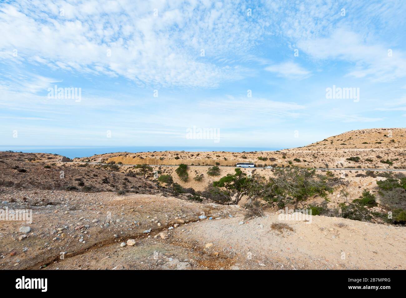 Straße durch die Wüste in Marokko mit Atlantik im Hintergrund Stockfoto