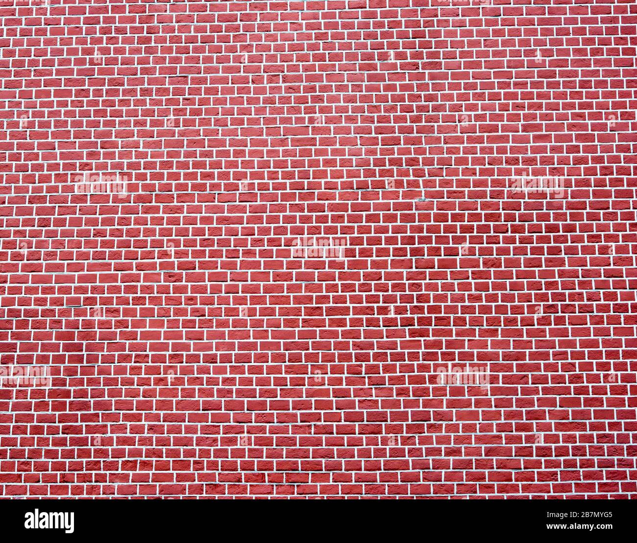 Eine glatte Ziegelwand in kalter rot-brauner Farbe mit weißen Gelenken. Strukturierter Hintergrund. Stockfoto