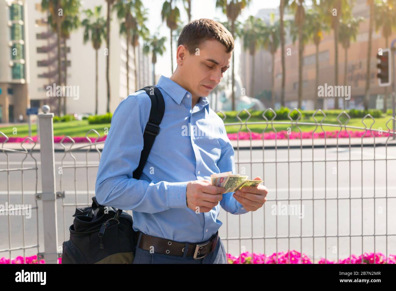 Ein männlicher Reisender hält in seinen Händen hält Papiergeld aus verschiedenen Ländern auf einer Stadtstraße. Stockfoto
