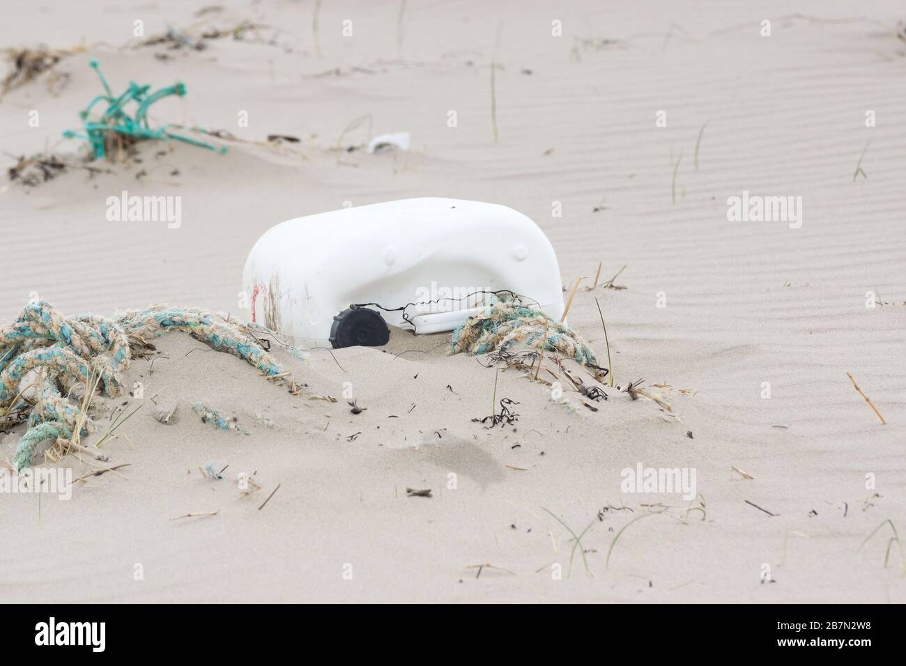 Kunststoffbehälter und Seil, die an einem Strand in Harlech UK gespült wurden, ein Beispiel für die Umweltverschmutzung im Meer Stockfoto