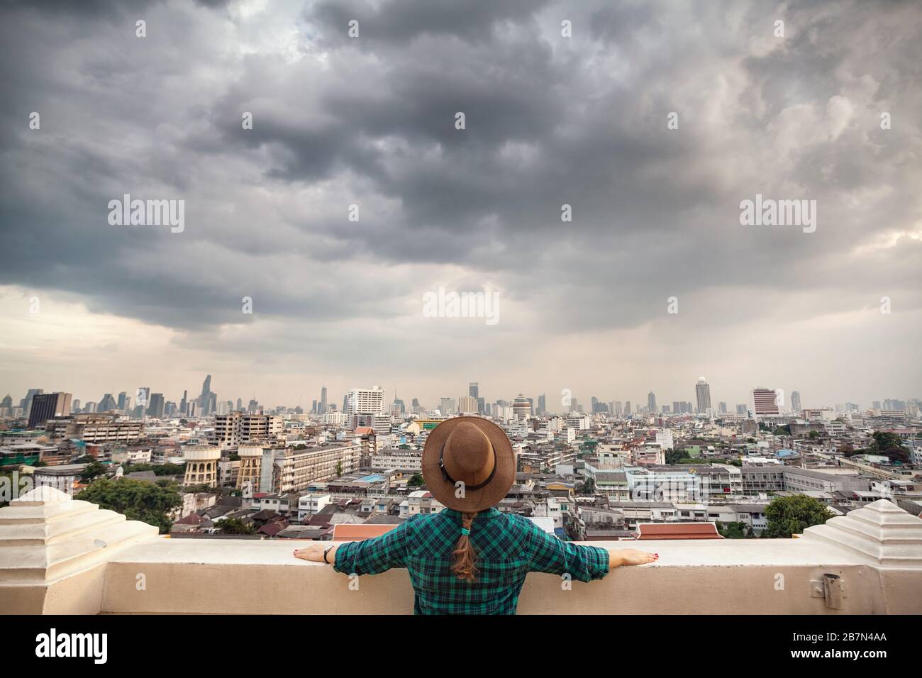 Tourist-Frau in Hut und grün kariertes Hemd Blick auf Bangkok City Panorama mit Wolkenkratzern des Geschäftsviertels von Golden Mountain Wat Saket vie Stockfoto