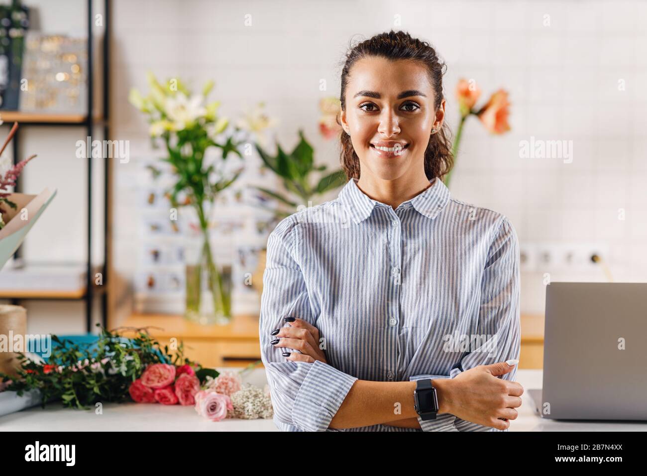 Porträt eines selbstbewussten Blumenbesitzers in ihrem Blumengeschäft und Blick auf eine Kamera Stockfoto