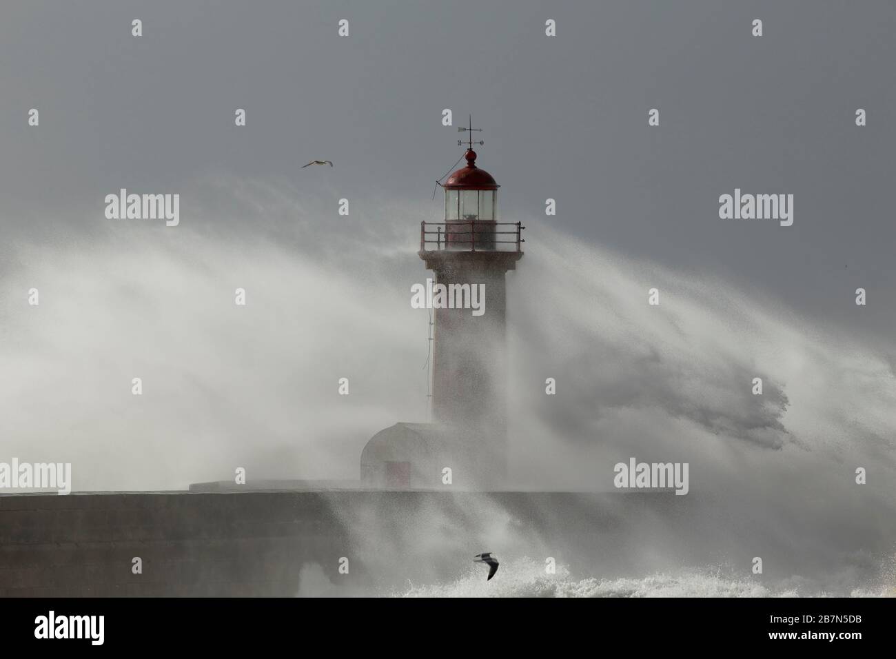 Stürmischer Tag an der Douro River Mouth mit Blick auf seinen alten Leuchtturm, der von Spray und Feuchtigkeit vom Spritzen der Wellen umgeben ist Stockfoto