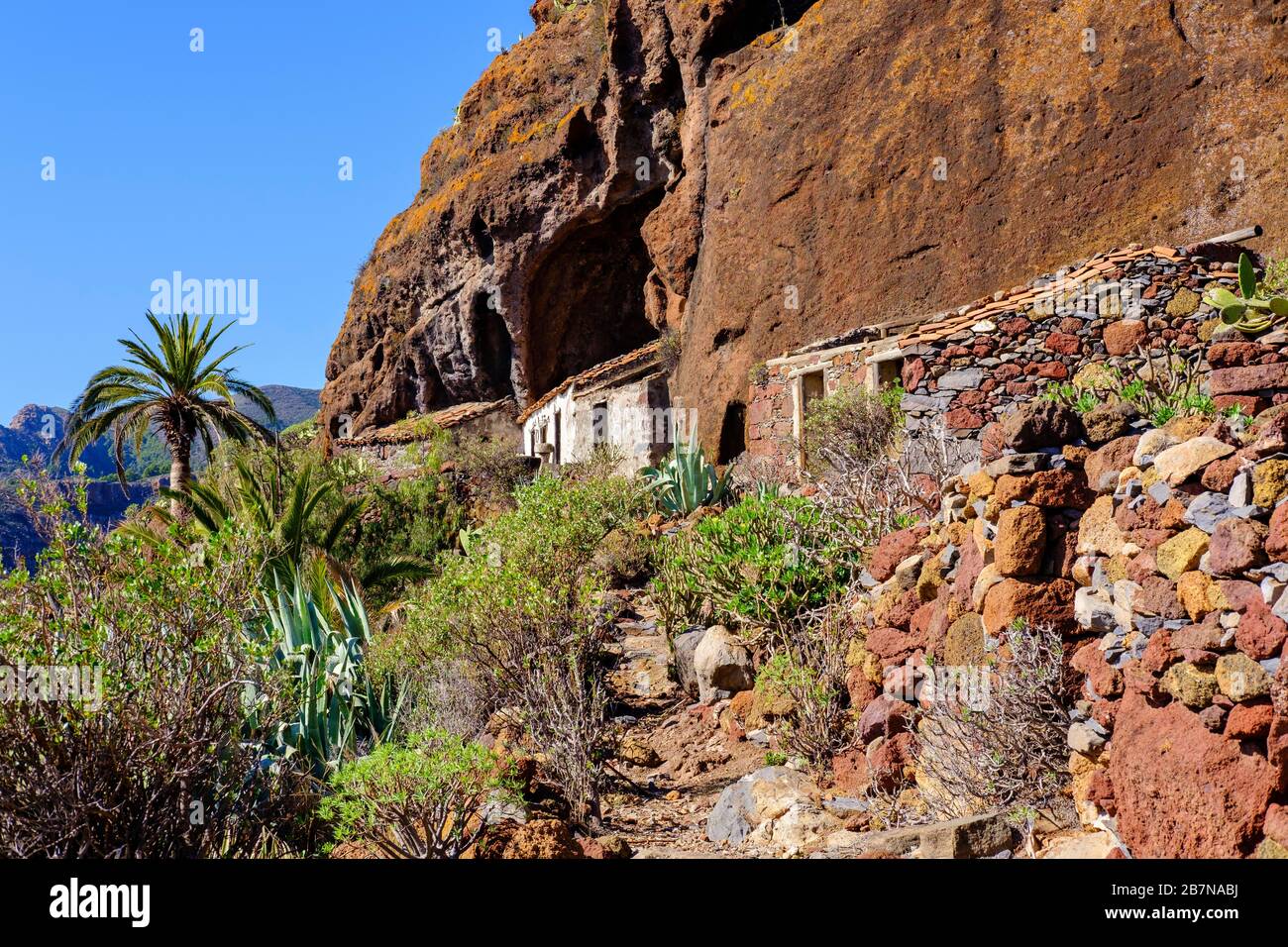 Verlassene Häuser unter Felswand, Tacalcuse, in der Nähe von San Sebastian, La Gomera, Kanarische Inseln, Spanien Stockfoto