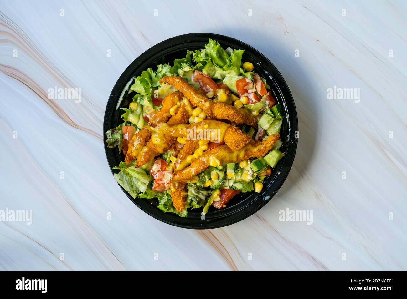 Nehmen Sie gesunden Cajun-Salat mit Hühnchenfingern und Sendesauce in der schwarzen Plastikplatte/Packung weg. Bio Fast Food. Stockfoto