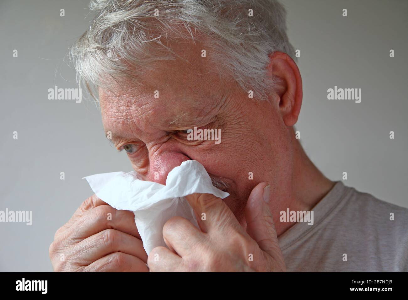 Der kranke Mann bläst mit einem Gewebe die Nase Stockfoto