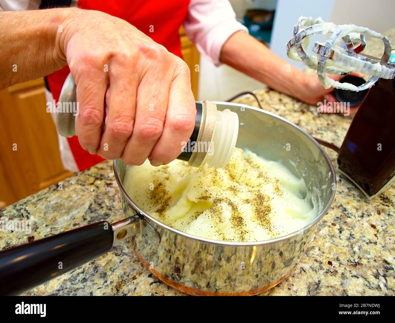 Ein Topf mit Kartoffelpüree wird vor dem Abendessen gewürzt. Stockfoto