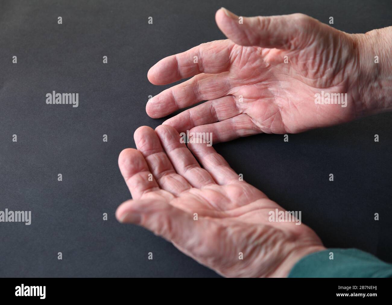 Die Hände älterer Männer auf einer dunklen Oberfläche mit Kopierraum Stockfoto