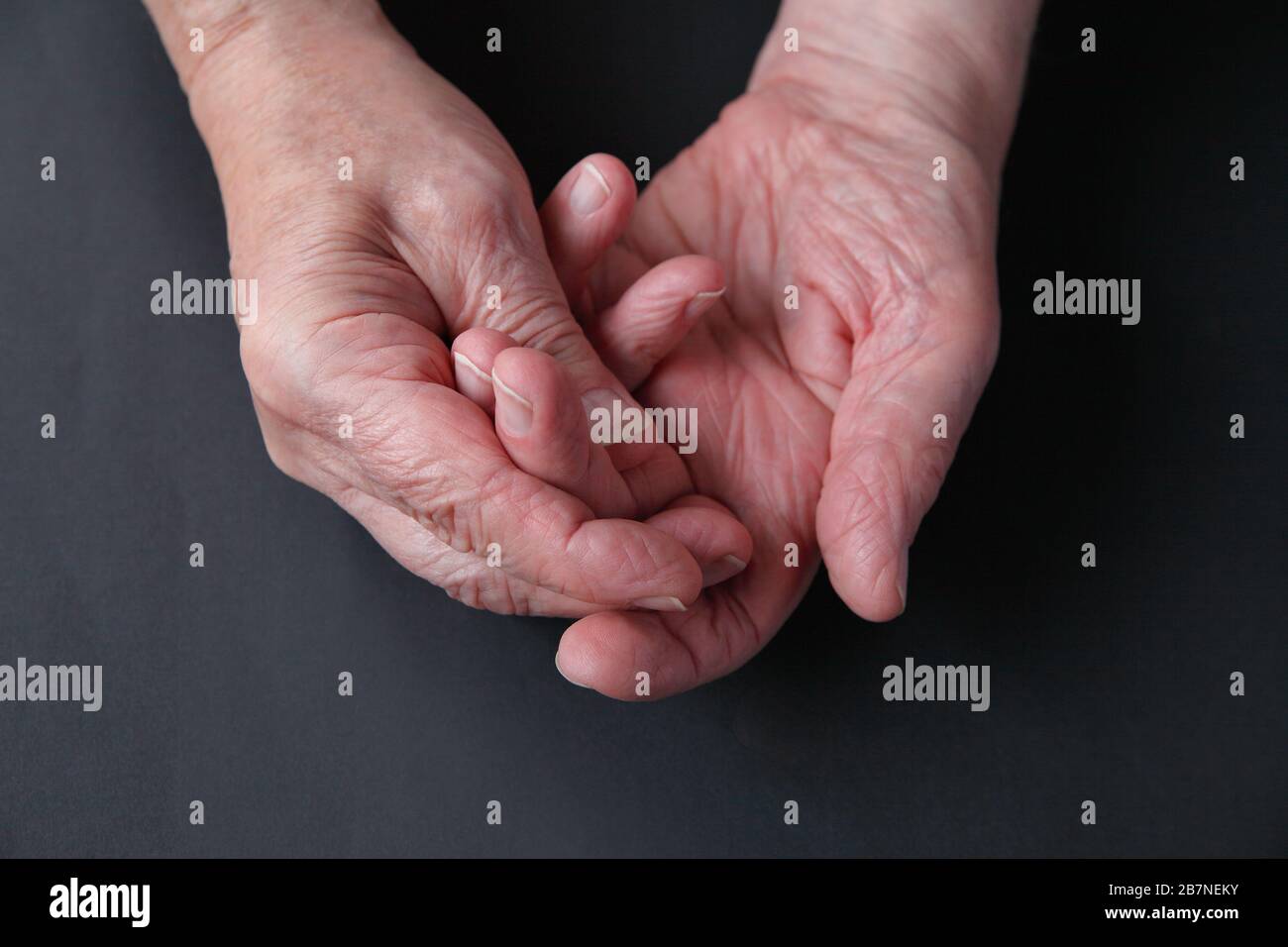 Ein älterer Mann hält seine Wunde Finger auf einem dunklen Hintergrund mit Platz für Text Stockfoto