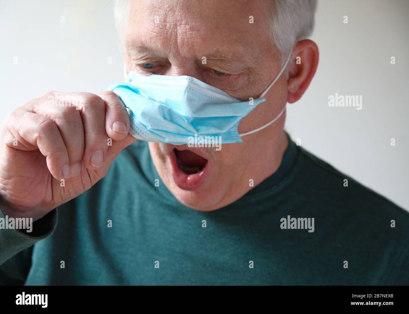 Der Obermann hebt seine medizinische Maske auf, um Luft zu schnappen Stockfoto