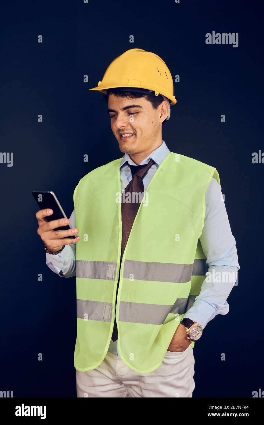 Junger Ingenieur mit Handy und Helm Stockfoto