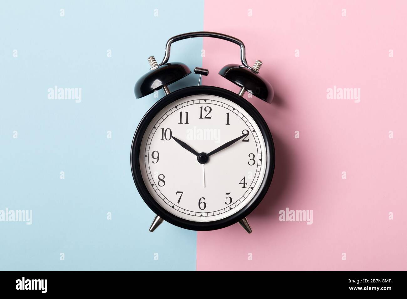 Schwarzer Vintage-Wecker auf blauem und rosafarbenem Hintergrund. Zeitkonzept Stockfoto Schwarzer Vintage-Wecker auf blauem und rosafarbenem Hintergrund. Zeitkonzept Stockfoto
