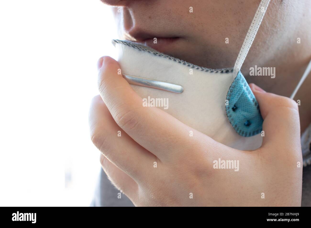 Eine Person legt eine Atemschutzmaske an oder entfernt sie. Seitenansicht Nahaufnahme. Hintergrund mit Kopierbereich. Gesundheits-Problemkonzept. Krankheit und Virus Stockfoto