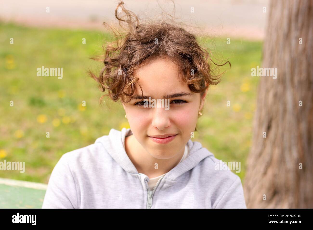 Portrait eines ruhigen, lockigen Teenager-Mädchens draußen im Park Stockfoto