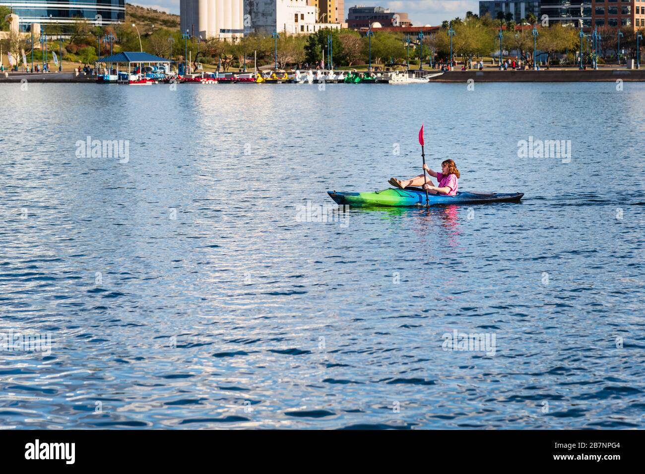Junge Rotkopffrau, Kajakfahren am Tempe Town Lake in Tempe, Arizona. Die perfekte Aktivität für soziale Distanzierungen in Zeiten der Pandemie. Stockfoto