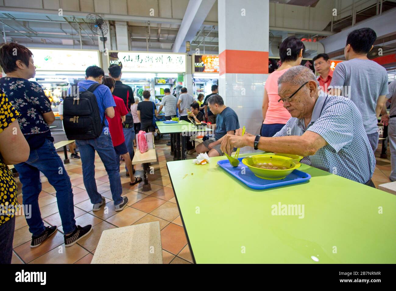 Die Leute warten auf und essen Essen in einem Falschzentrum in Singapur Stockfoto