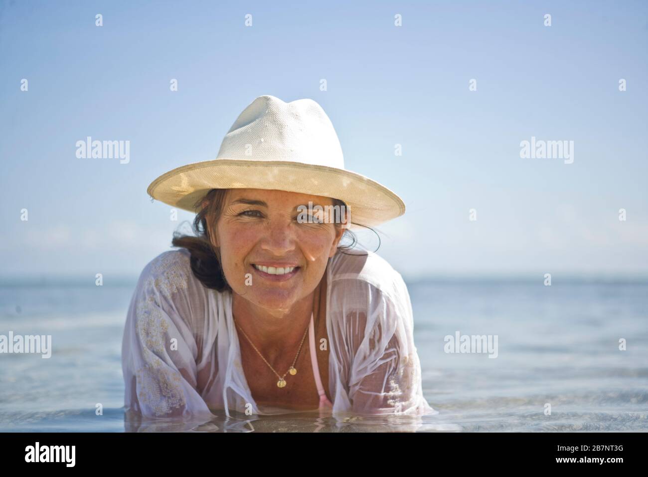 Porträt einer Frau, die im Wasser an einem Strand liegt. Stockfoto