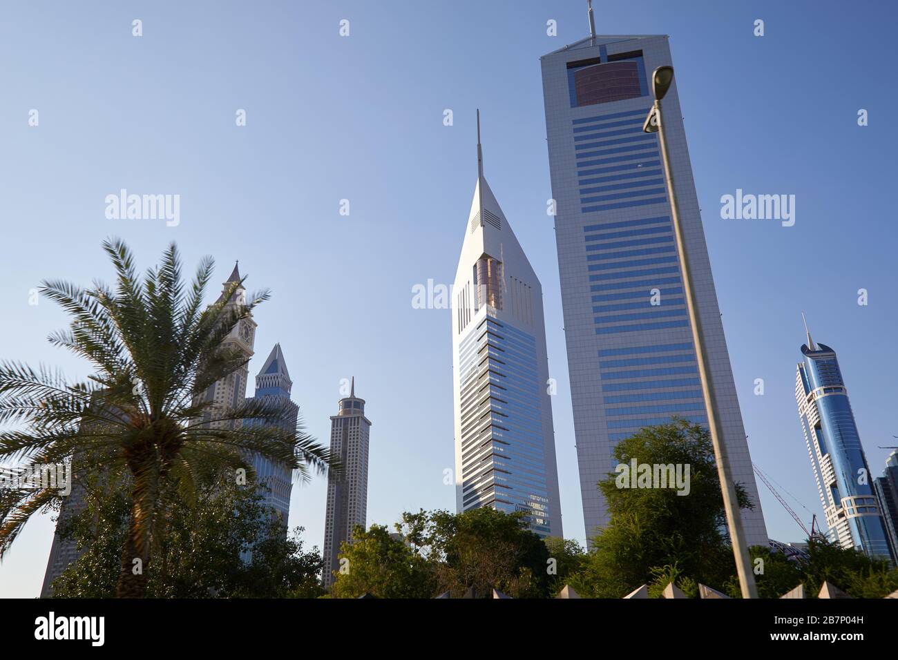 DUBAI, VEREINIGTE ARABISCHE EMIRATE - 23. NOVEMBER 2019: Dubai Financial District, moderne Doppelhochhäuser und Palmen an einem sonnigen Tag, blauer Himmel Stockfoto