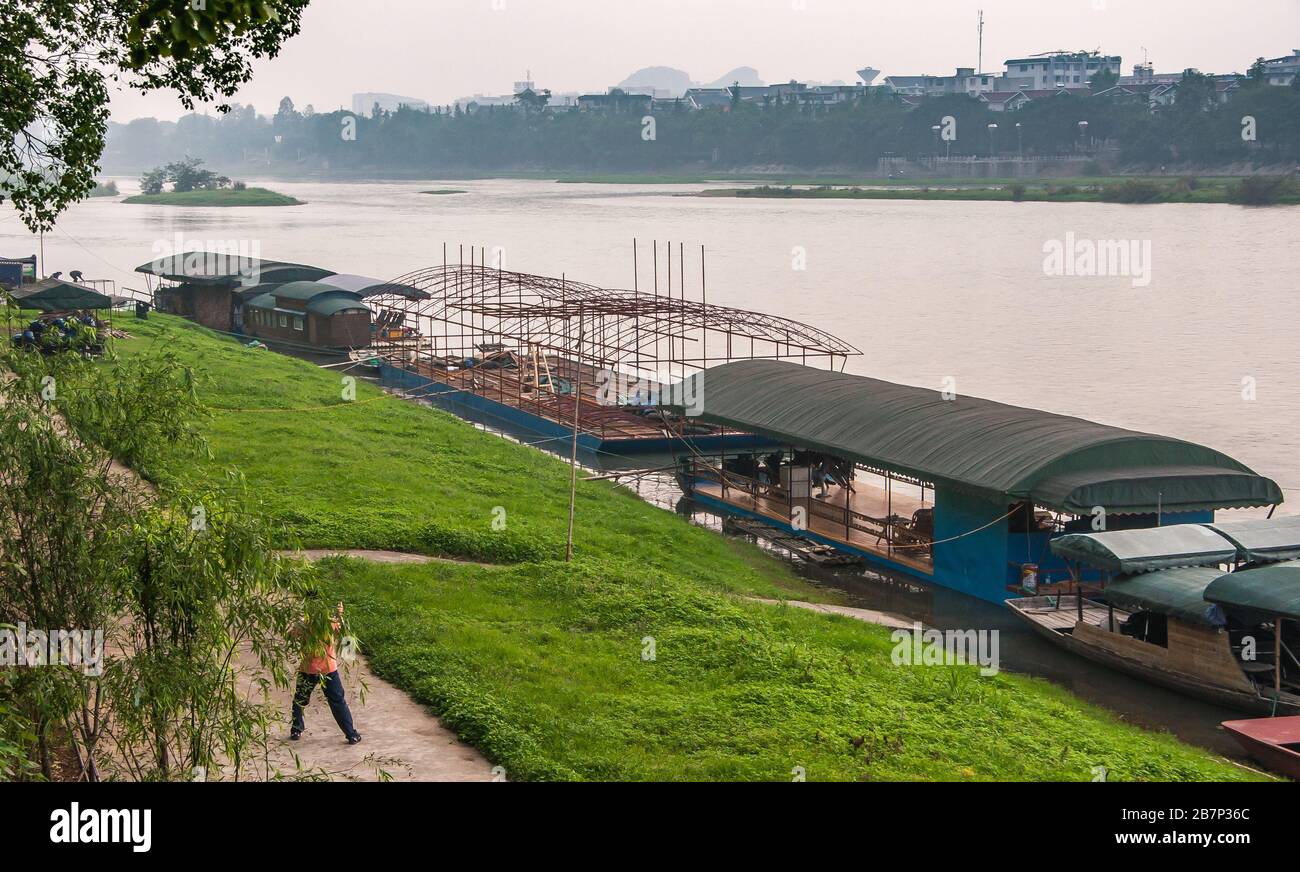 Guilin, China - 11. Mai 2010: Jiefang Brücke über die Innenstadt von Li River. Unterhaltungsbargen im Bau. Inseln im Fluss, silberner Nebelhimmel und B. Stockfoto