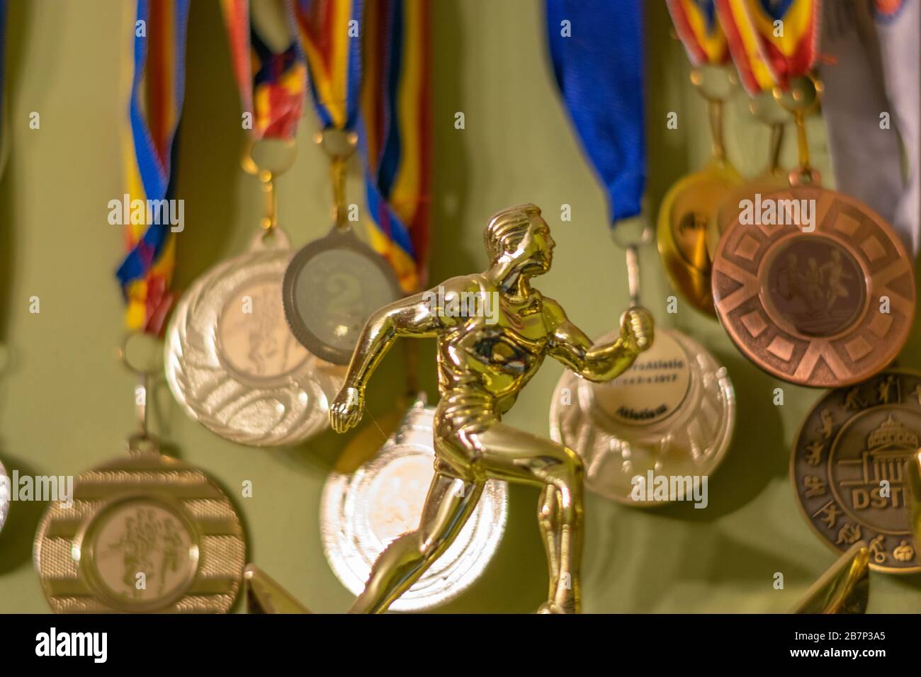 Eine goldene Trophäe, die einen Sportler symbolisiert, der läuft, und viele Medaillen im Hintergrund, Bukarest, Rumänien Stockfoto