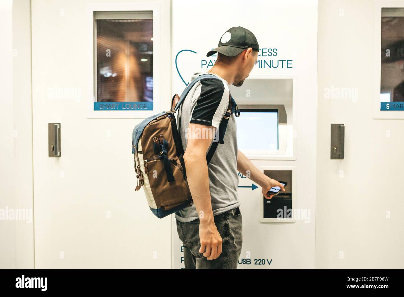 Der Tourist nutzt oder bezahlt den Zugang zur Selbstbedienungslounge oder zur eleganten Lounge am Flughafen, um sich zu entspannen. Stockfoto