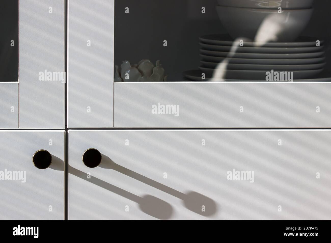 Harte und weiche Schatten auf einem weißen Schrank mit Utensilien. Stockfoto