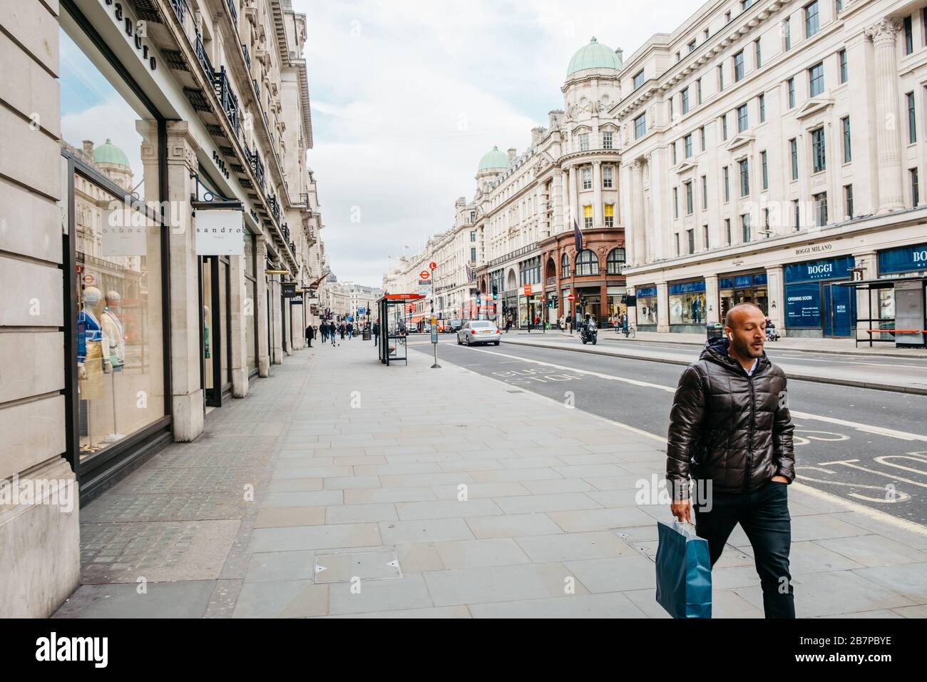 Ein einsamer Mann läuft während der Corona-Virus/Covid-19-Pandemie in London, Großbritannien, auf einer leeren Regent's Street. März 2020. Stockfoto
