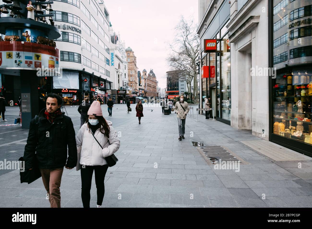 Menschen und Touristen, die Gesichtsmasken tragen, während sie durch einen leeren Leicester Square, London, Großbritannien während des Corona-Virus-Ausbruchs spazieren. Stockfoto