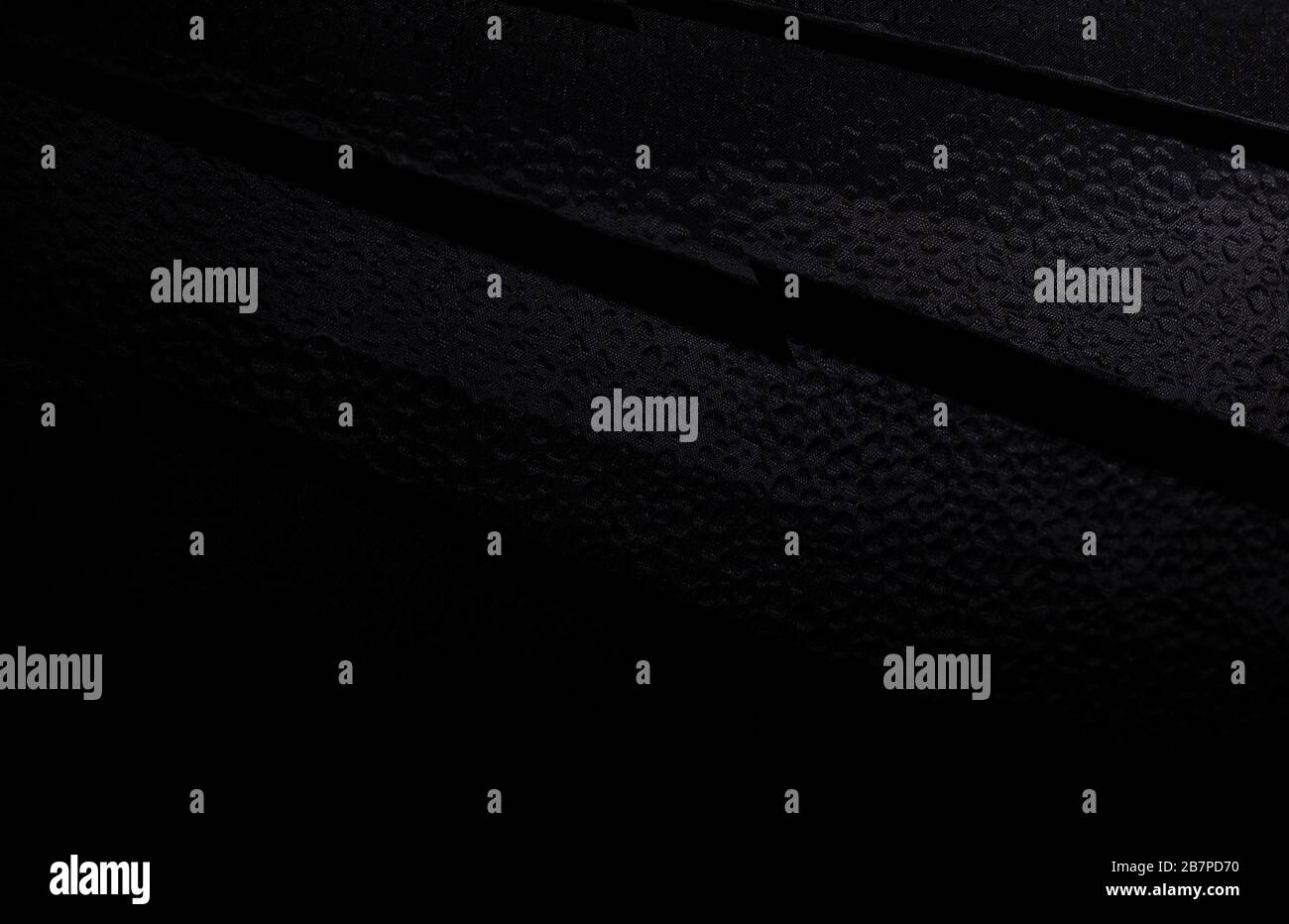 Schwarzer abstrakter Hintergrund aus dunklem Stoff mit feinen Hohlräumen Stockfoto