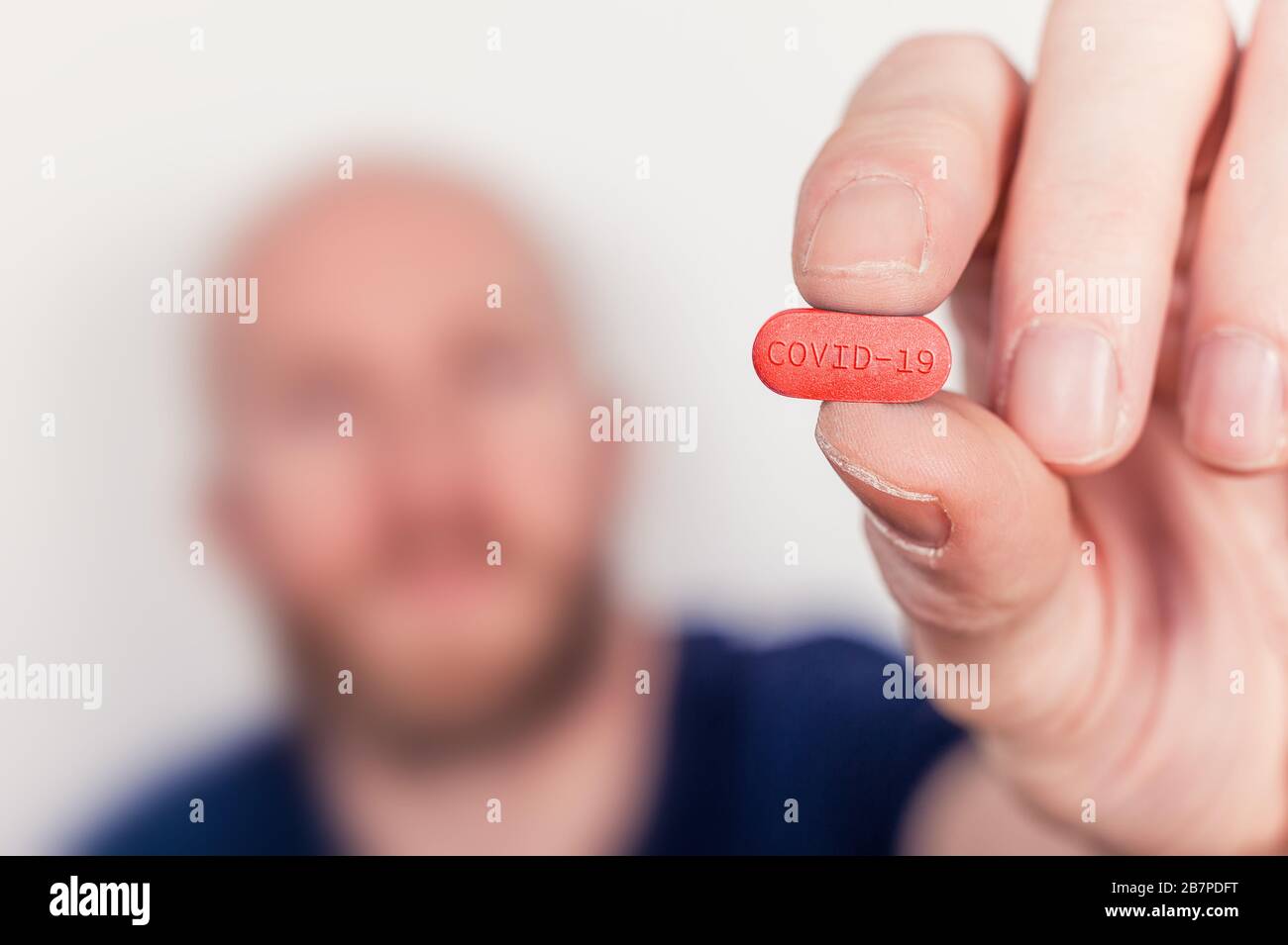 Abbildung: Heilmittel gegen Coronavirus Covid-19, Mann mit einer Tablette mit Covid-19-Etikett. Stockfoto